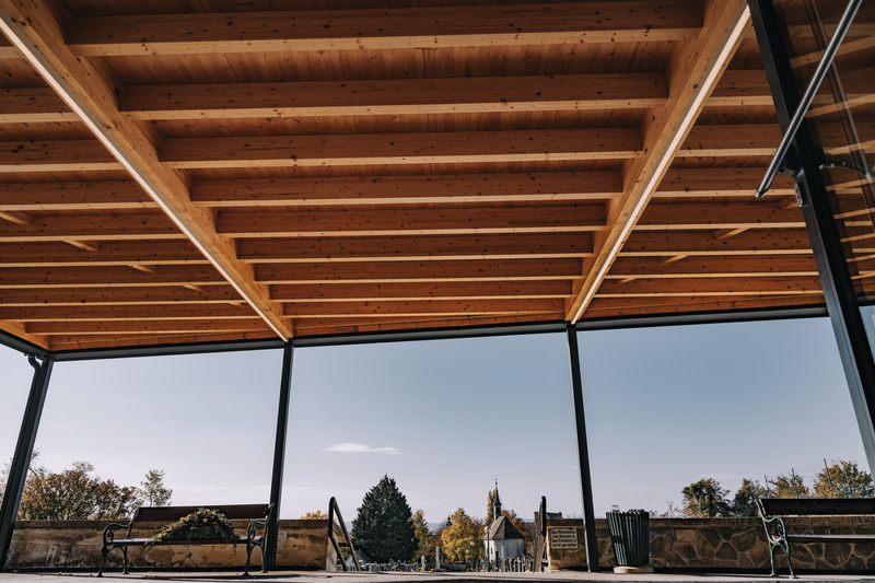 Vier Männer in traditioneller bayerischer Kleidung, einer hält ein Bierglas und lächelt bei einer Veranstaltung im Freien.