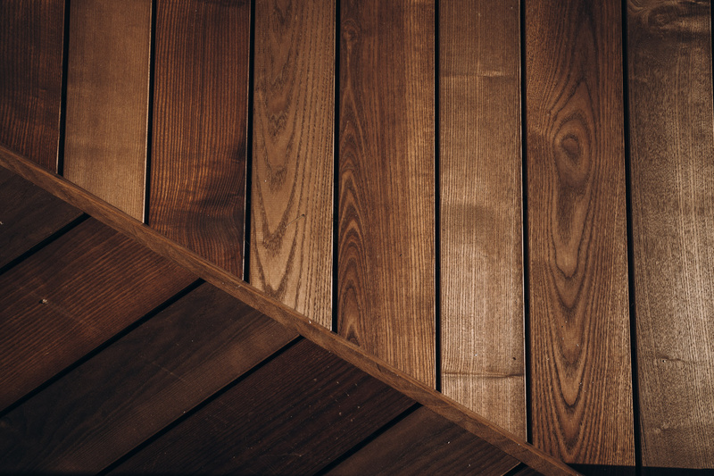 Diagonal und vertikal angeordnete Holzbretter, die unterschiedliche Farbtöne und Holzmaserungen aufweisen.
