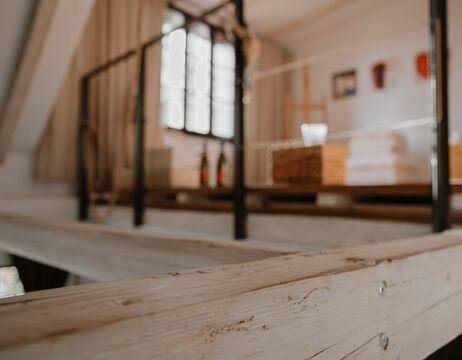 Weißes hölzernes Loft-Geländer mit unscharfem Hintergrund eines gemütlichen, sonnenbeschienenen Raums und Kunstzubehör.