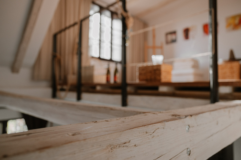 Weißes hölzernes Loft-Geländer mit unscharfem Hintergrund eines gemütlichen, sonnenbeschienenen Raums und Kunstzubehör.