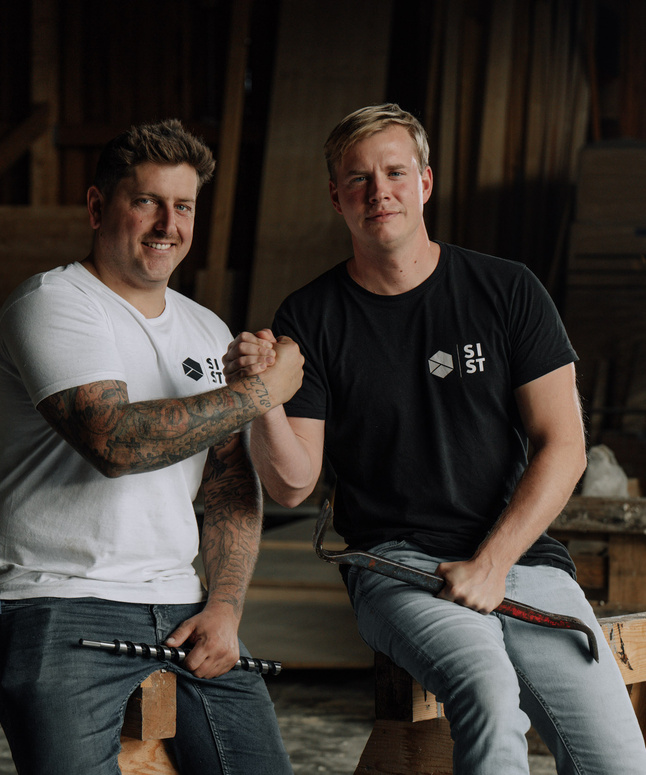 Zwei Gläser Weißwein und eine Weinflasche auf einem Holztisch im Freien, mit unscharfem Hintergrund.