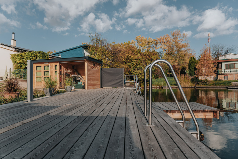 Eine lächelnde Frau in traditioneller Kleidung hält ein Tablett mit Gläsern und einer Karaffe in einem rustikalen Restaurant.