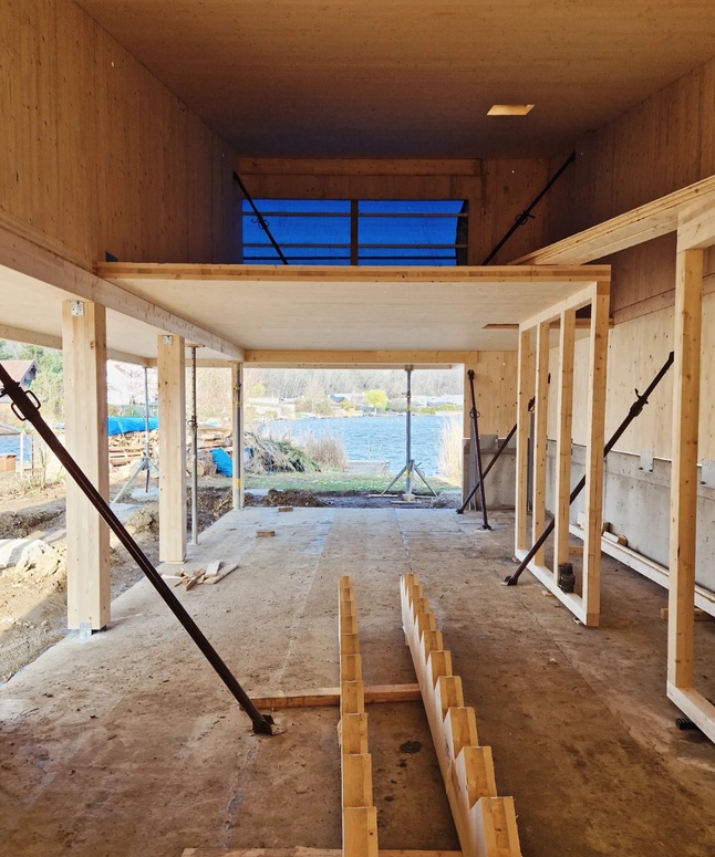 Panoramablick auf die Skyline einer Stadt mit einem Fluss und grünen Feldern unter einem klaren blauen Himmel.