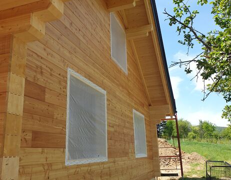 Ein neu gebautes Holzhaus mit kunststoffverkleideten Fenstern und einem blauen Himmel im Hintergrund.