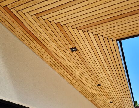 Moderne Holzlattendecke mit Einbaulampen, die ein geometrisches Muster über einer hellen Wand bilden.